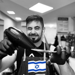 אבי הספר מחייף למצלמה עם מייבש שיער ביד