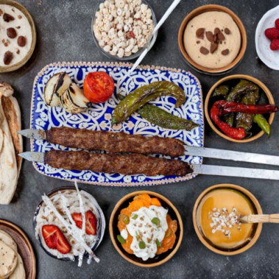 מבט על שולחן מלא סלטים ובמרכז שני שיפודי קבב