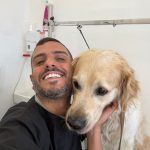 בחור צעיר מחייך ומחזיק כלב
